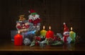 New year`s composition: a toy Santa Claus, a Reindeer and a Snowman, burning colored candles and gifts Royalty Free Stock Photo