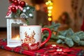 New Year`s Cup of hot drink in front of the Christmas tree on a red tablecloth stands near the candlestick. Winter Royalty Free Stock Photo