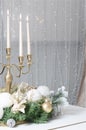 New Year`s decorations and a golden candlestick with burning candles stand on the surface of a white grand piano