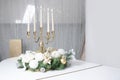 New Year`s decorations and a golden candlestick with burning candles stand on the surface of a white grand piano