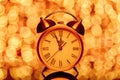 New year`s eve midnight. Retro alarm clock whose pointer shows five to twelve on festive bokeh background Royalty Free Stock Photo