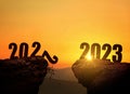 New Year`s Eve 2023 on the mountain at sunset, concept. 2022 and 2023 on the cliff at sunrise, creative idea. 2022 falls into the