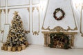 New Year`s interior with a decorated Christmas tree and a fireplace in the living room in white tones,New Year`s gifts lie under Royalty Free Stock Photo