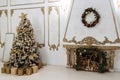 New Year`s interior with a decorated Christmas tree and a fireplace in the living room in white tones,New Year`s gifts lie under Royalty Free Stock Photo