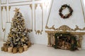 New Year`s interior with a decorated Christmas tree and a fireplace in the living room in white tones,New Year`s gifts lie under Royalty Free Stock Photo