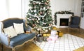New Year`s interior with ÃÂhristmas-tree by the fireplace, balls and lights. Comfortable blue sofa with pillows in the room. Royalty Free Stock Photo