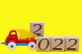 2022 new year`s number on wooden blocks on thev toy dump truck on yellow background Royalty Free Stock Photo