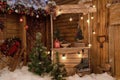 New Year`s photo zone with snow near a wooden house. Christmas decor: toys, Christmas trees, skis, garland, firewood, glowing Royalty Free Stock Photo