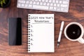 New Year\'s Resolutions 2025 text on note pad, pen, smartphone, coffee on wood desk