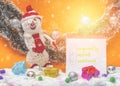 New Year`s snowman in red suit and notebook with inscription `FAQ`. Bright festive surroundings. Orange background. Royalty Free Stock Photo