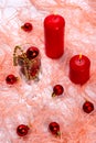 New Year\'s still life: a glass with red Christmas tree toys and two red candles on a pink background Royalty Free Stock Photo