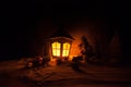 New Year\'s still-life postcard lamp covered in snow with glowing candle at night