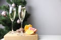 New Year\'s still life two glasses of champagne and fruit stand against background of decorated Christmas tree against a gra Royalty Free Stock Photo