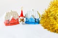 New Year`s toys. a snowman in a big red cap stands between the red and blue houses. gold tinsel is nearby Royalty Free Stock Photo