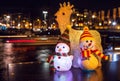 New Year`s toys snowmen and deer pose against night canals of Amsterdam.