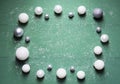 New Year`s white and gray balls lie on a green wooden background with snow.