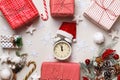 New Year`s winter composition. Alarm clock santa hat Christmas boxes with gift fir branches on a white background.