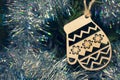 New Year`s wooden toy - a mitten, hanging on a Christmas tree decorated with shiny garlands. Selective focus. Copy space. Royalty Free Stock Photo