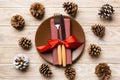 New Year set of plate and utensil on wooden background. Top view of holiday dinner decorated with pine cones. Christmas time Royalty Free Stock Photo