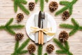 New Year set of plate and utensil on wooden background. Top view of holiday dinner decorated with pine cones. Christmas time Royalty Free Stock Photo