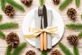 New Year set of plate and utensil on wooden background. Top view of holiday dinner decorated with pine cones. Christmas time Royalty Free Stock Photo