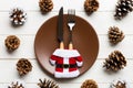 New Year set of plate and utensil on wooden background. Top view of holiday dinner decorated with pine cones. Christmas time Royalty Free Stock Photo