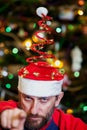 Man with beard in Christmas hat on background of tree Royalty Free Stock Photo