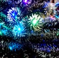 New Year tinsel with neon lights on a Christmas tree closeup Royalty Free Stock Photo