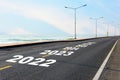 New year 2022 to 2027 on asphalt road with marking line for given direction and sea landscape