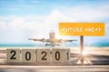 New year 2020 to 2021 and commercial plane with future ahead word on wooden sign on tropical beach background Royalty Free Stock Photo