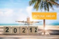 New year 2021 to 2022 and commercial plane with future ahead word on wooden sign on tropical beach background Royalty Free Stock Photo