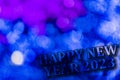 New Year 2023. Translucent numbers of the year on a blue-toned background of bright lights out of focus. Horizontal design.