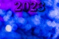 New Year 2023. Translucent numbers of the year on a blue-toned background of bright lights out of focus. Horizontal design. Royalty Free Stock Photo