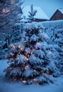 New Year tree covered with snow and decorated with Christmas lights Royalty Free Stock Photo