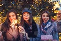 New Year. Women friends burning sparklers in Lviv by Christmas tree. Girls holding gift boxes. Night party under snow Royalty Free Stock Photo