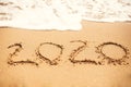 2020 New Year. 2020 written on sandy beach with wave foam at sea beach. Happy New Year. Tropical celebration. Inscription on Royalty Free Stock Photo