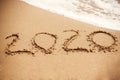 2020 New Year. 2020 written on sandy beach with wave foam at sea beach. Happy New Year. Tropical celebration. Inscription on Royalty Free Stock Photo