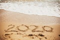 2020 New Year. 2020 written on sandy beach with wave foam at sea beach. Happy New Year. Tropical celebration. Inscription on Royalty Free Stock Photo