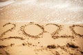 2020 New Year. 2020 written on sandy beach with wave foam at sea beach. Happy New Year. Tropical celebration. Inscription on Royalty Free Stock Photo