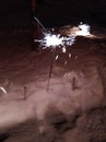 A New Year's fireworks display is lit, standing in the snow. Sparklers