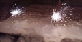 A New Year's fireworks display is lit, standing in the snow. Sparklers