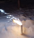 A New Year's fireworks display is lit, standing in the snow. Sparklers