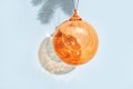 New years ball, glass transparent orange colored holiday toy on blue background. Christmas greeting card