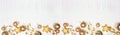 New Years Eve border banner of confetti, streamers and gold decorations, top view over a white wood background Royalty Free Stock Photo