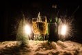New Years Eve celebration background with pair of flutes and bottle of champagne with christmas tree on snow on dark background. Royalty Free Stock Photo