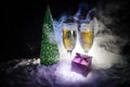 New Years Eve celebration background with pair of flutes and bottle of champagne with christmas tree on snow on dark background. Royalty Free Stock Photo