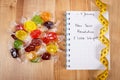 New years resolutions written in notebook, candies and tape measure Royalty Free Stock Photo