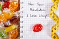 New years resolutions written in notebook, candies and tape measure Royalty Free Stock Photo