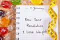 New years resolutions written in notebook, candies and tape measure Royalty Free Stock Photo