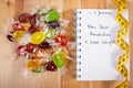 New years resolutions written in notebook, candies and tape measure Royalty Free Stock Photo